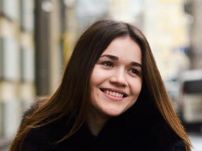 Mujer sonriente en la calle, disfrutando del día en un entorno urbano.